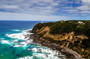 Landscape view of cliff by ocean with lighthouse and house