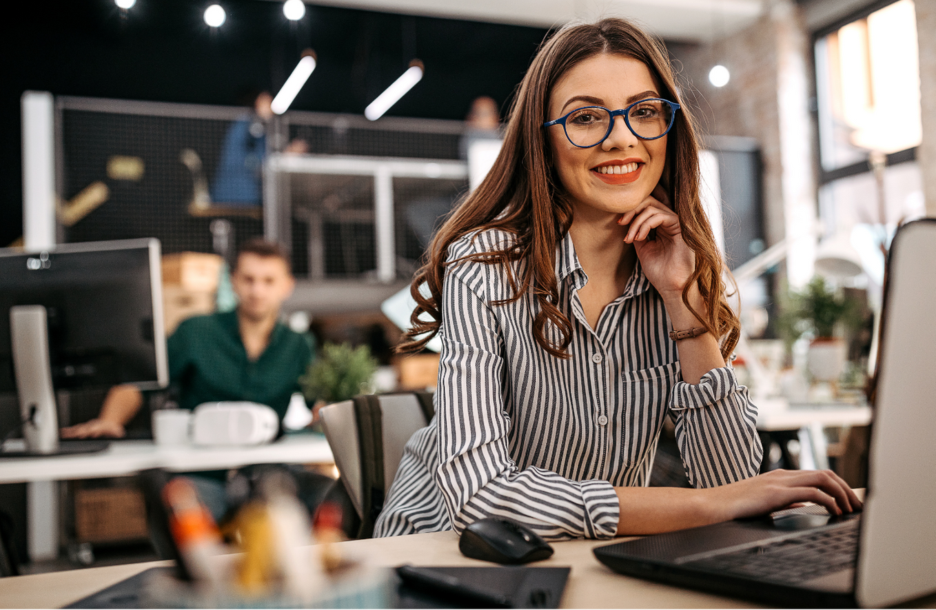 Woman in striped shirt and glasses, sitting at computer